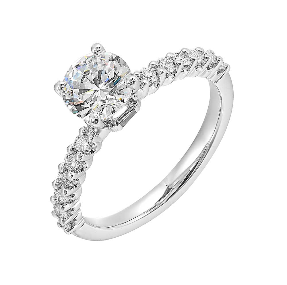 A dazzling round solitaire takes center stage,  held by a sleek shank adorned with sparkling diamonds is a perfect choice for any occasion.