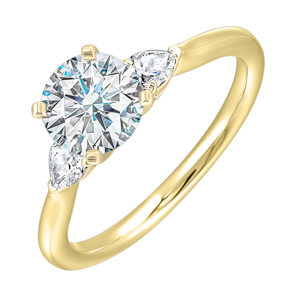 Stunning engagement ring features a round brilliant cut diamond in the center of a three stone setting,  adorned on either side by a smaller pear diamond set on the tapered shank.