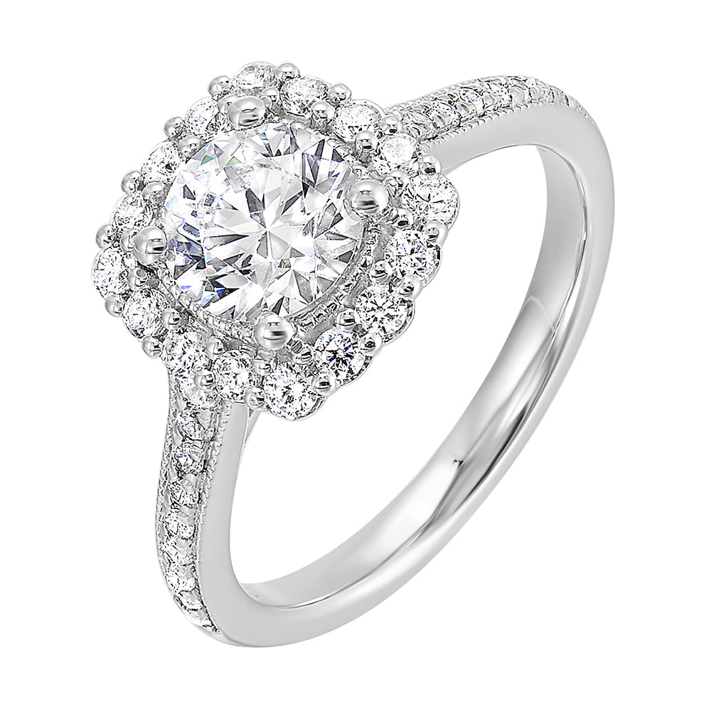 This romantic engagement ring features a round solitare with milgrain details adorned with a delicate cushion style diamond halo and a thin pave band.